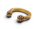 a close up of a gold bracelet with two balls on it