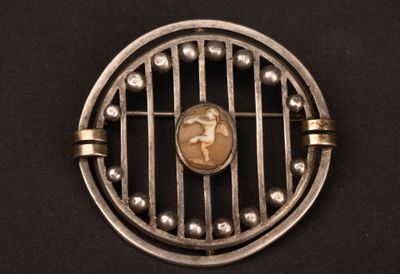 une broche ancienne en argent représentant une femme dans une cage