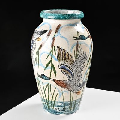 a vase with a bird design on it sitting on a table