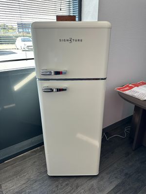 a white refrigerator sitting next to a window in a room
