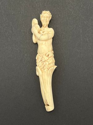 une figurine en ivoire représentant un homme tenant un oiseau, posée sur une surface noire
