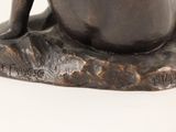a bronze statue of a man sitting on a rock