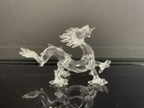 une figurine en verre représentant un dragon posé sur une table