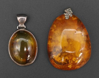 deux morceaux d'ambre et un pendentif en argent sur un fond noir
