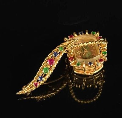 un gros plan d'une broche en or sertie de pierres multicolores