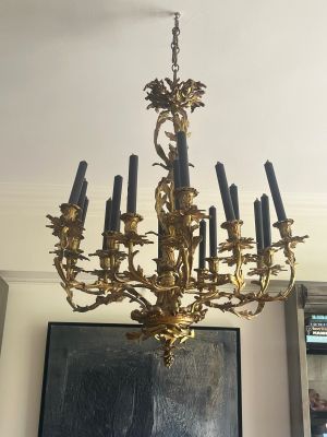 a gold chandelier with black candles in a living room