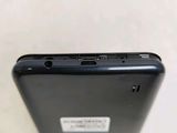 the back of a black cell phone sitting on top of a white table