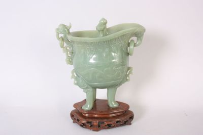 un vase vert posé sur un socle en bois, sur fond blanc