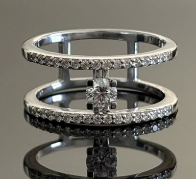 une bague en diamant posée sur une surface miroitante, avec son reflet