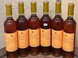 six bottles of wine are lined up in a row on a table