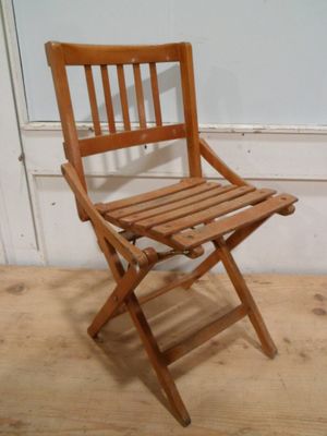 une chaise pliante en bois assise sur un sol en bois dur