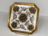 une assiette décorée d'or et de blanc, ornée de fleurs
