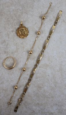 a gold necklace, bracelet, and ring laying on a table