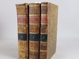 two old books sitting on top of each other on a white surface