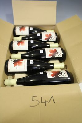 six bottles of wine in a cardboard box on a table