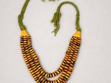 a necklace made of yellow and green beads on a white surface