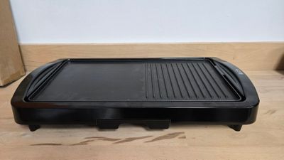 une photo représentant un barbecue posé sur un plancher en bois, avec une boîte en arrière-plan