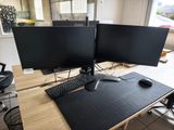 deux écrans d'ordinateur posés sur un bureau en bois