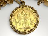 a close up of a gold bracelet with a coin on it