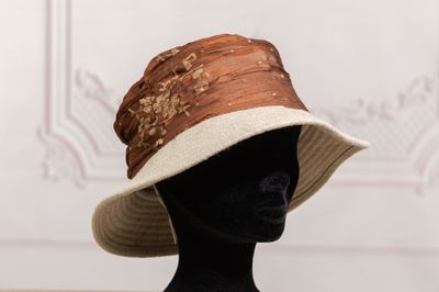 chapeau marron et blanc posé sur une tête de mannequin exposée
