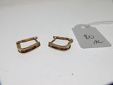 Deux paires de boucles d'oreilles sont posées sur une table, accompagnées d'une étiquette de prix