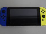 La Nintendo Switch Lite est posée sur une table, accompagnée d'une manette bleue et jaune.