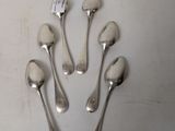 six silver spoons are arranged in a circle on a white surface