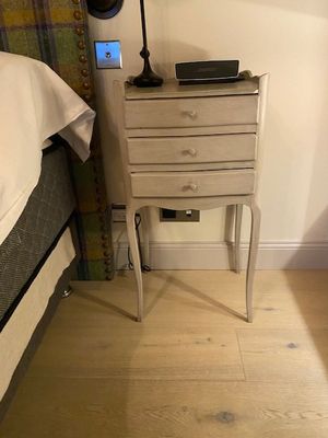 une petite table sur laquelle est posée une lampe, à côté d'un lit