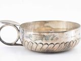 a silver cup with a handle on a white surface