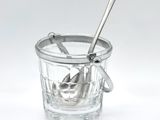 a glass cup with a spoon in it on a white surface