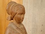 a wooden statue of a woman sitting on a table