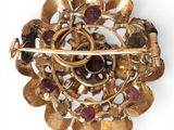 an image of a gold broochle with garnetts and stones