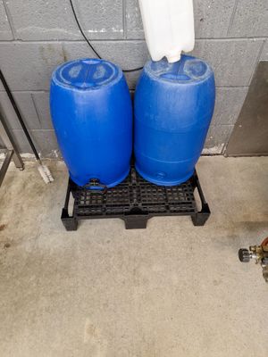 Deux fûts vides en PVC bleu avec palette en PVC noir