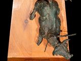 sculpture of a frog on a wooden block with a black background