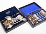 des cuillères en argent et des cuillères à soupe dans un étui posé sur une surface blanche
