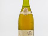 une vieille bouteille de vin posée sur une table blanche