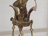 a gold vase with a bird on it on a stand