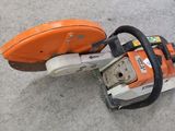 an orange and white chainsaw sitting on the ground next to a wall