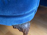an image of a blue velvet chair with a lion foot rest