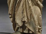 an old statue of a man in a cloak holding a sword