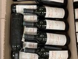 plusieurs bouteilles de vin dans un carton posé sur le sol