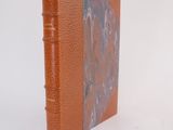 an orange book sitting on top of a white table next to a white wall