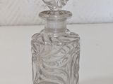 a clear glass bottle with a silver lid sitting on a white surface