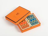 an orange box with two playing cards in it on a white surface