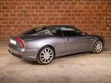 an image of a silver sports car parked in front of a brick wall
