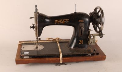 une machine à coudre noire posée sur un support en bois