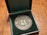 an old silver medal in a black box on a wooden table