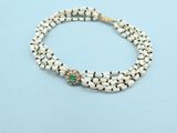 a white beaded bracelet with a gold clasp and a green stone bead