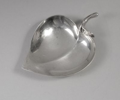 un plat ancien en argent, orné d'une poignée en forme de feuille sur un fond blanc