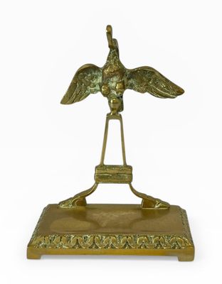 un oiseau en laiton posé sur un socle, sur fond blanc